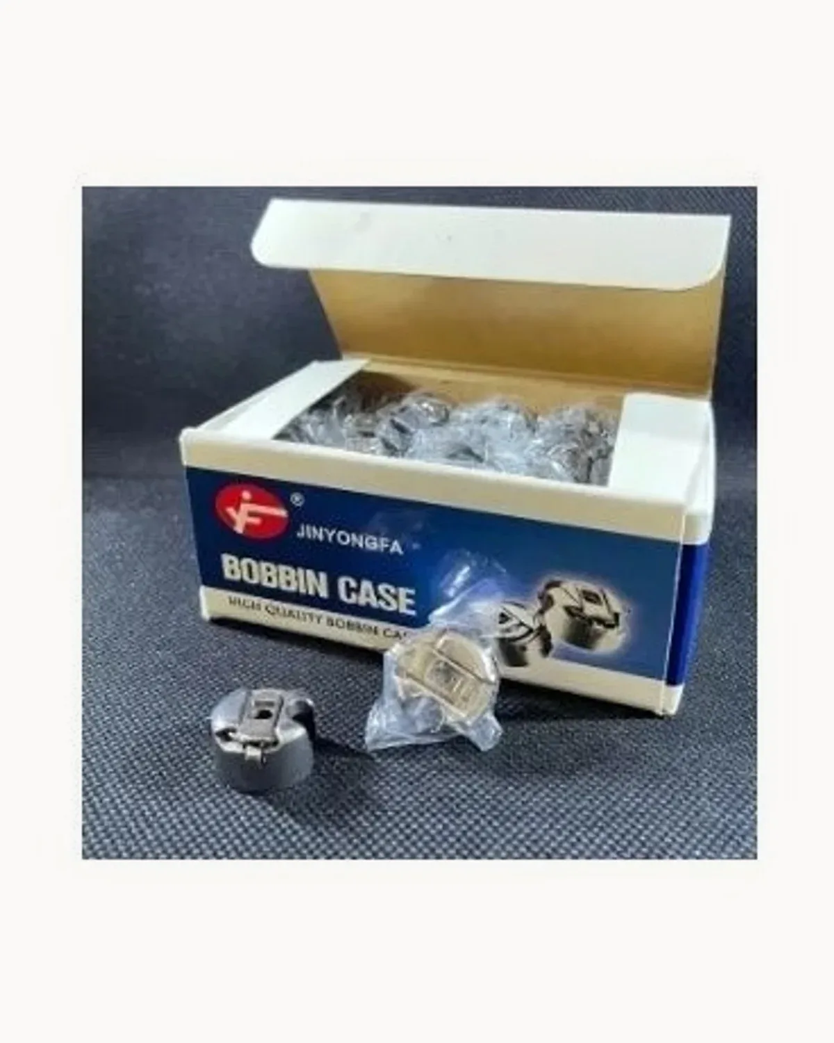 A Jinyongfa bobbin case box with two loose bobbin cases beside it