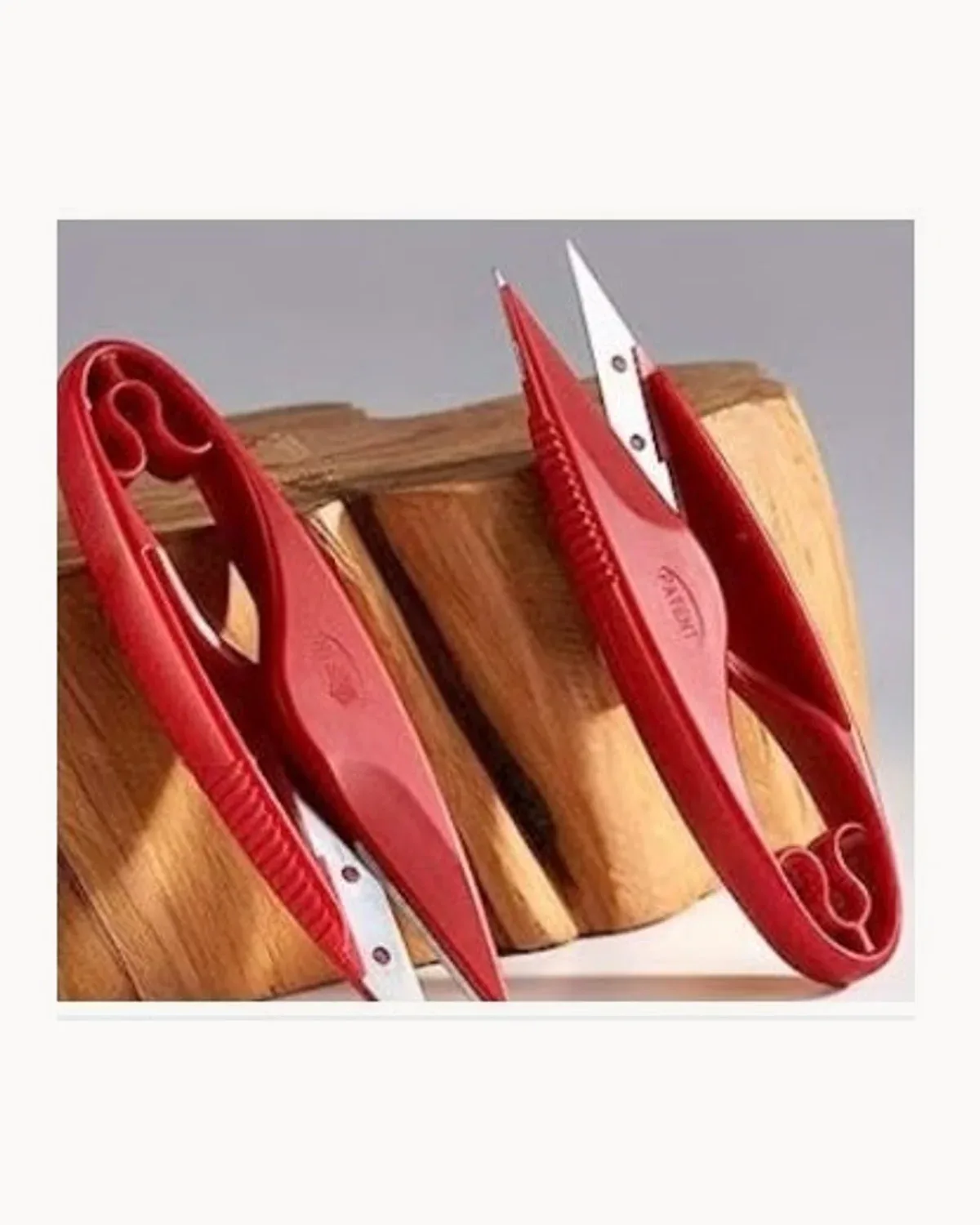 Two red PIN thread snips resting on a wooden block