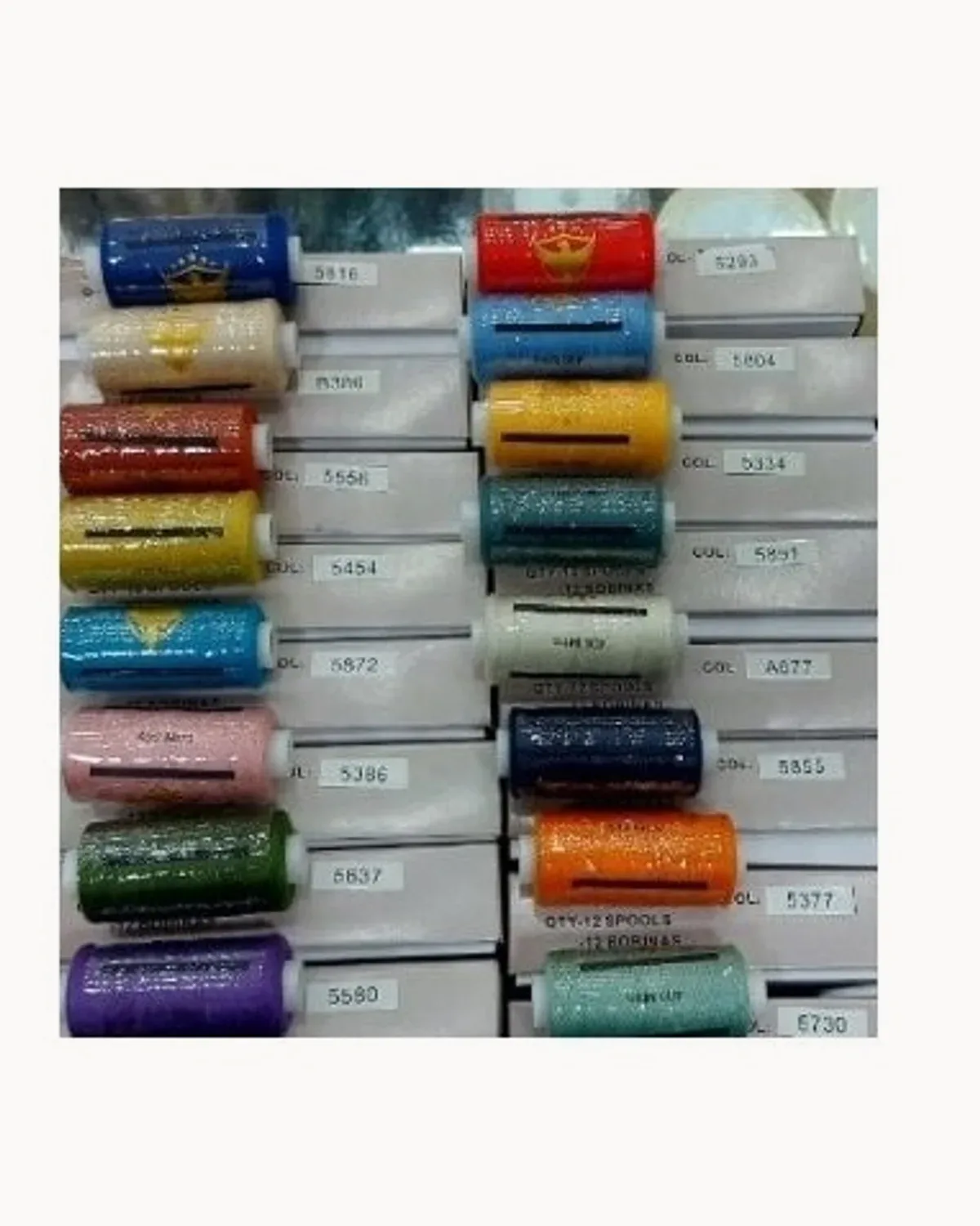 A rack of coloured polyester thread spools with their colour numbers